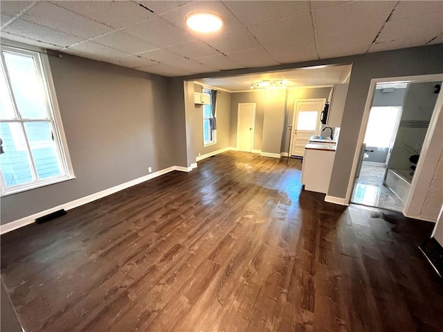 empty room with a drop ceiling, dark hardwood / wood-style floors, and sink