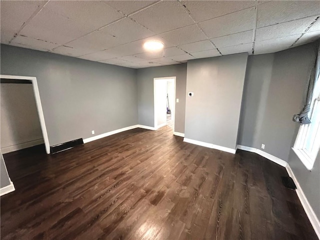 spare room featuring dark hardwood / wood-style flooring and a drop ceiling