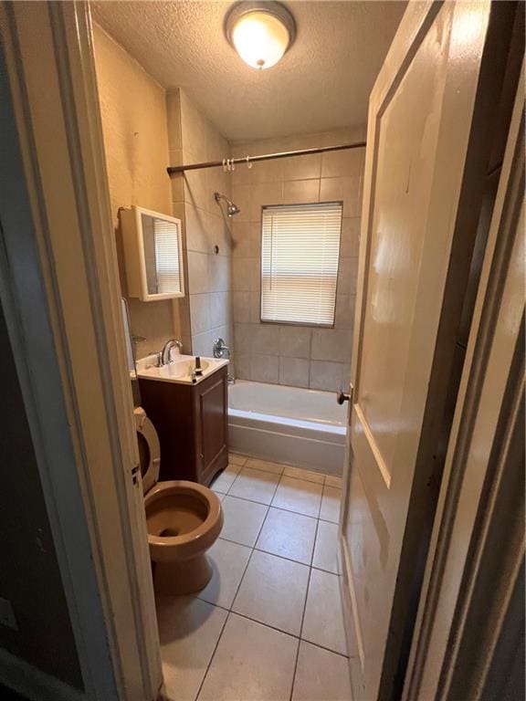 full bathroom with vanity, a textured ceiling, tile patterned flooring, toilet, and tiled shower / bath