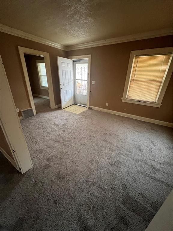 empty room with carpet, a textured ceiling, and ornamental molding