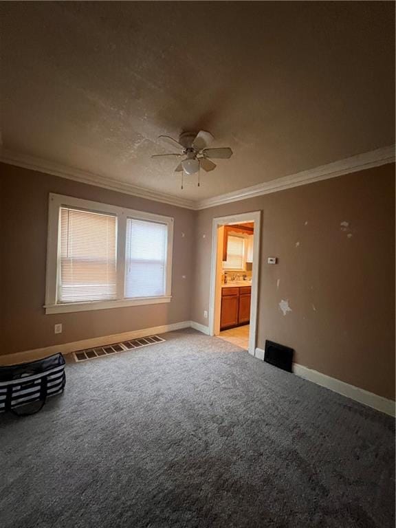 carpeted spare room featuring crown molding and ceiling fan