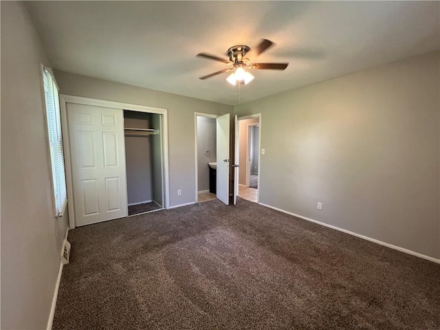 unfurnished bedroom with dark colored carpet, ceiling fan, and a closet