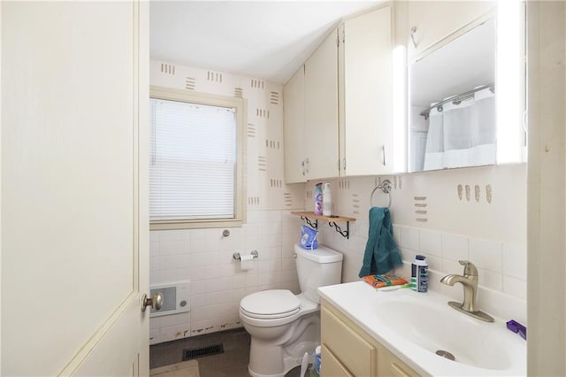 bathroom featuring vanity, tile walls, and toilet