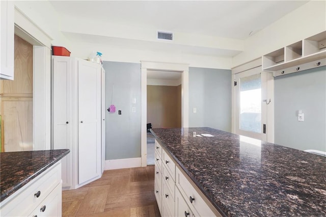 kitchen featuring dark stone countertops, light parquet floors, and white cabinets