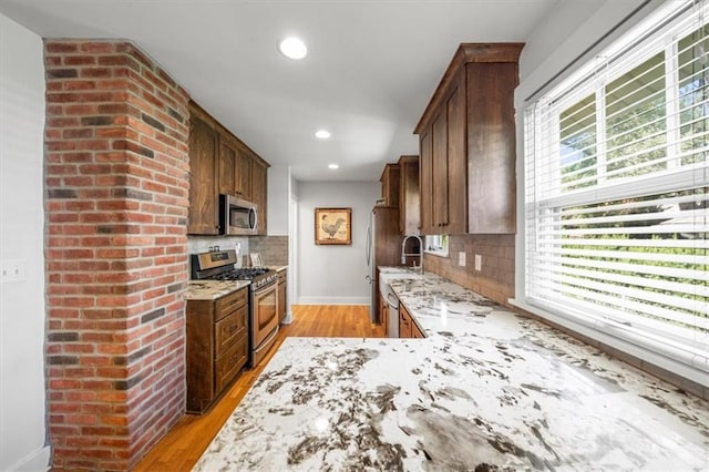 kitchen featuring light stone countertops, stainless steel appliances, plenty of natural light, and tasteful backsplash