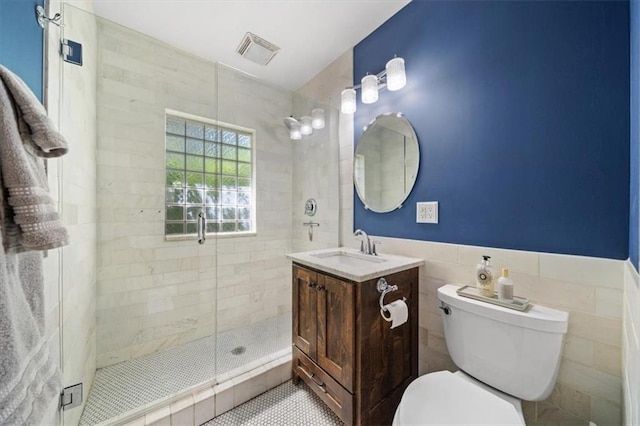 bathroom with vanity, tile patterned floors, tile walls, toilet, and a shower with door