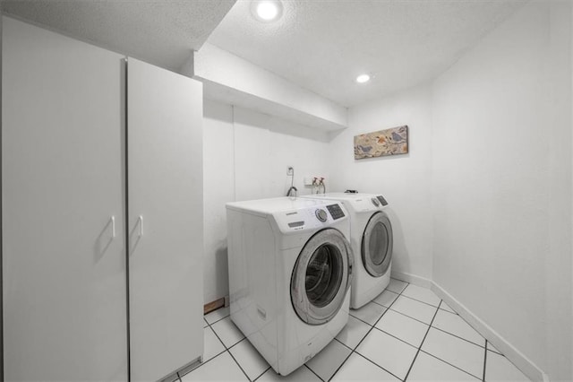 washroom with a textured ceiling, washing machine and dryer, and light tile patterned flooring