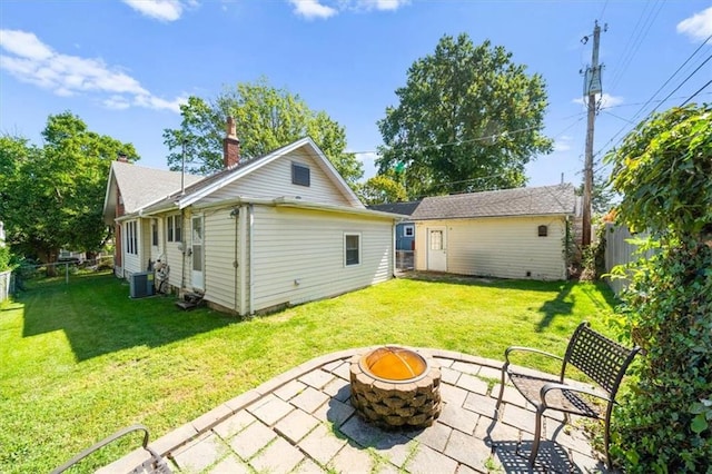 back of property featuring a lawn, a patio, central AC unit, and an outdoor fire pit