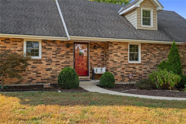 3438 N 123rd St, Kansas City, KS 66109 - view of exterior entry featuring brick siding, a yard, and a shingled roof