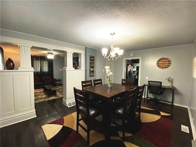 dining room with ceiling fan with notable chandelier, ornate columns, a textured ceiling, and dark hardwood / wood-style floors