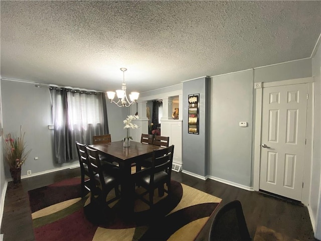 dining space with a textured ceiling, a chandelier, and dark hardwood / wood-style floors