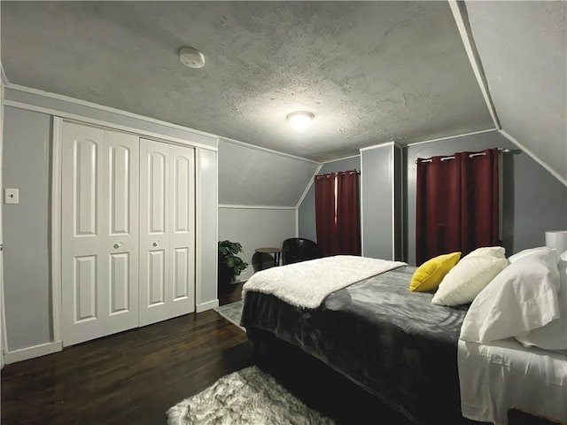 bedroom with a closet, dark hardwood / wood-style floors, a textured ceiling, and vaulted ceiling