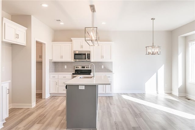 kitchen featuring stainless steel appliances, white cabinetry, sink, and pendant lighting