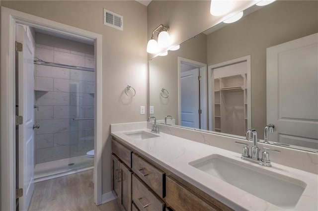 bathroom featuring a shower with door, vanity, hardwood / wood-style flooring, and toilet