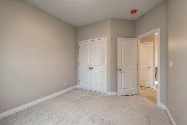 unfurnished bedroom with light colored carpet and a closet