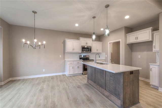 kitchen with white cabinetry, stainless steel appliances, sink, and pendant lighting