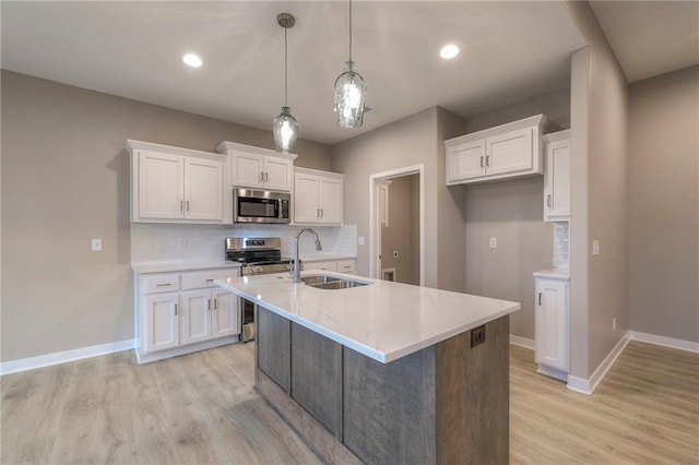 kitchen with pendant lighting, stainless steel appliances, sink, and white cabinets