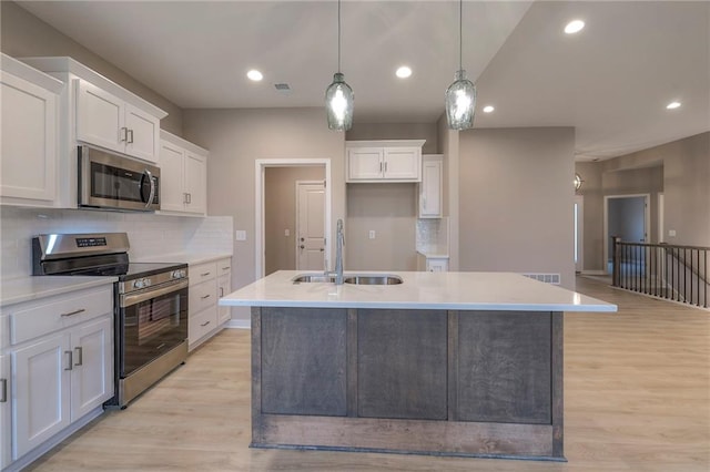 kitchen featuring pendant lighting, stainless steel appliances, sink, and white cabinets