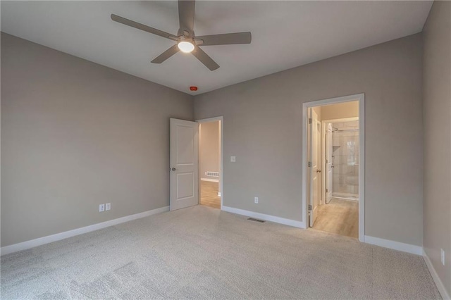 unfurnished bedroom featuring ensuite bath, light colored carpet, and ceiling fan