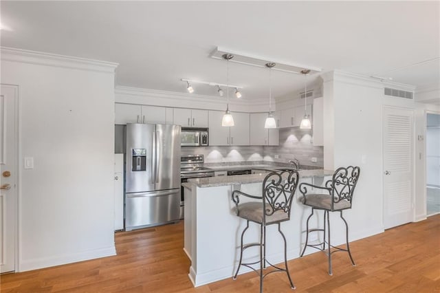 kitchen featuring ornamental molding, appliances with stainless steel finishes, and light hardwood / wood-style floors