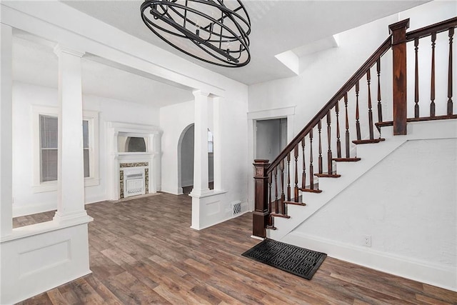 entrance foyer featuring stairway, ornate columns, wood finished floors, and a fireplace