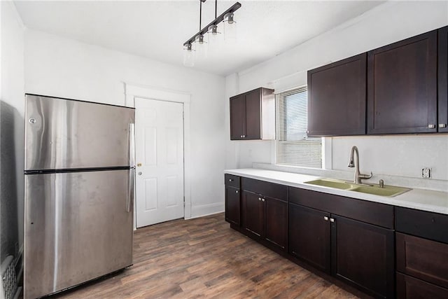kitchen featuring a sink, freestanding refrigerator, dark brown cabinetry, and dark wood-type flooring