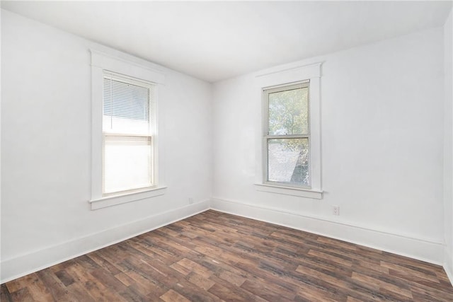 empty room featuring baseboards and dark wood finished floors