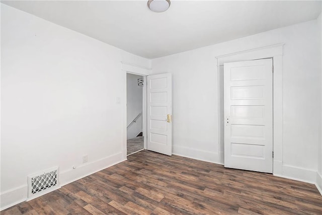 unfurnished bedroom with baseboards, dark wood finished floors, and visible vents