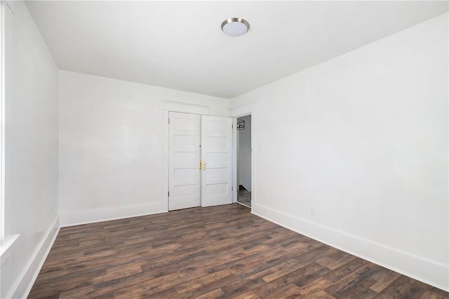 spare room with dark wood-style flooring and baseboards