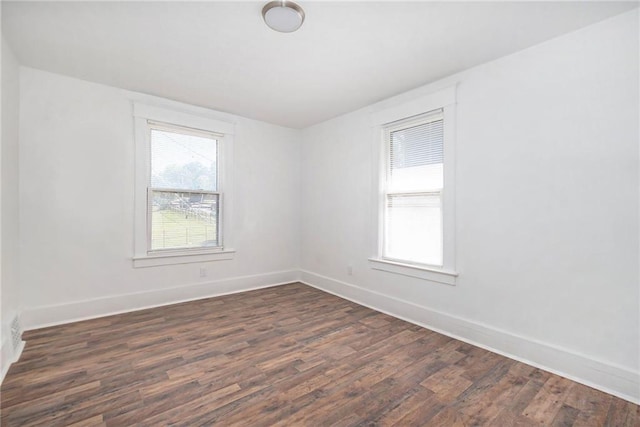 spare room featuring dark wood-style flooring and baseboards