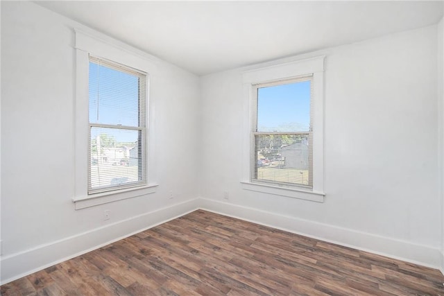 unfurnished room with a healthy amount of sunlight, baseboards, and dark wood-style floors