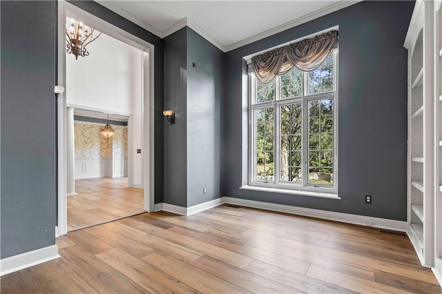 empty room featuring crown molding, light hardwood / wood-style floors, and a notable chandelier