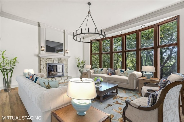 living room featuring hardwood / wood-style flooring, a high ceiling, an inviting chandelier, a fireplace, and crown molding