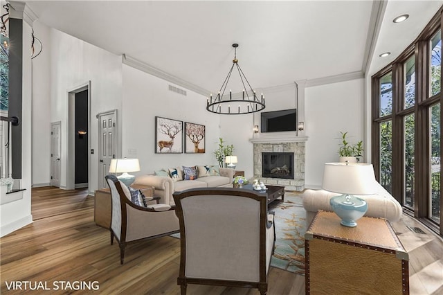 living room with crown molding, a fireplace, an inviting chandelier, and hardwood / wood-style flooring