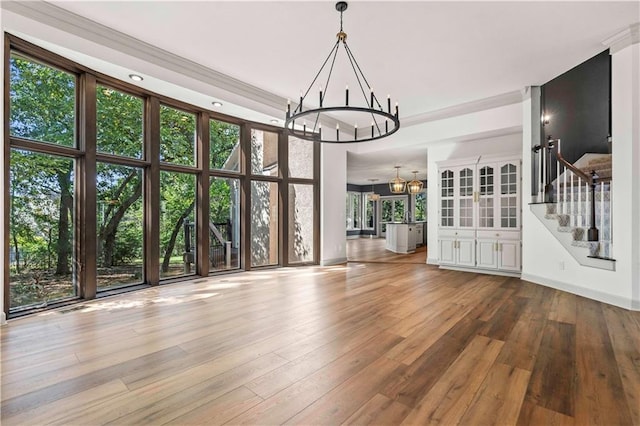 unfurnished dining area with an inviting chandelier, light hardwood / wood-style flooring, and a high ceiling