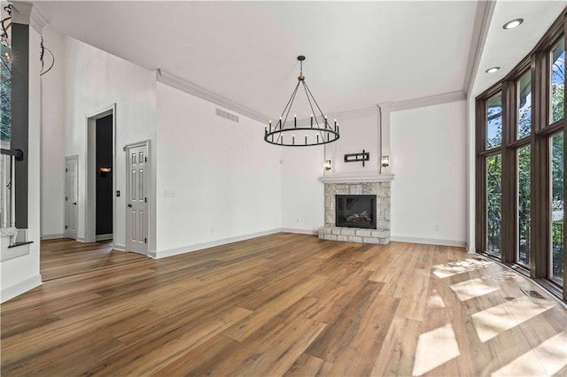 unfurnished living room with crown molding, a stone fireplace, a towering ceiling, and hardwood / wood-style floors