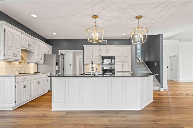 kitchen featuring decorative light fixtures, appliances with stainless steel finishes, light wood-type flooring, and white cabinetry