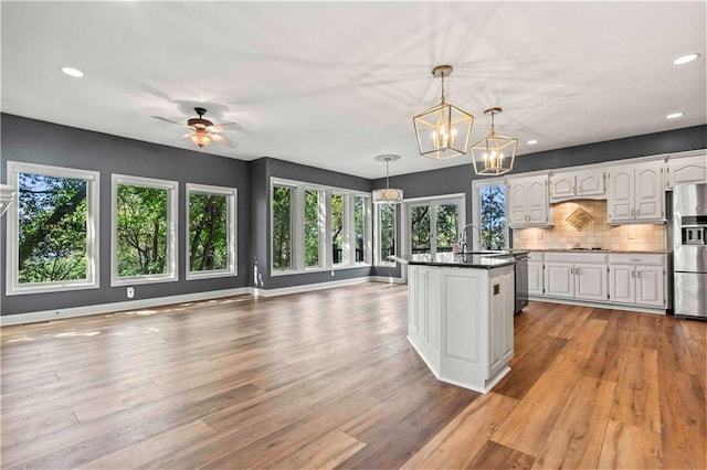 kitchen with light hardwood / wood-style flooring, stainless steel appliances, white cabinetry, and decorative light fixtures