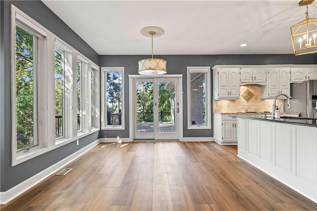 kitchen with light hardwood / wood-style flooring, white cabinetry, hanging light fixtures, and stainless steel fridge with ice dispenser