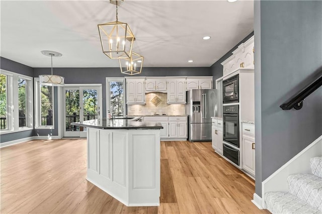 kitchen featuring hanging light fixtures, black appliances, light hardwood / wood-style floors, and white cabinets