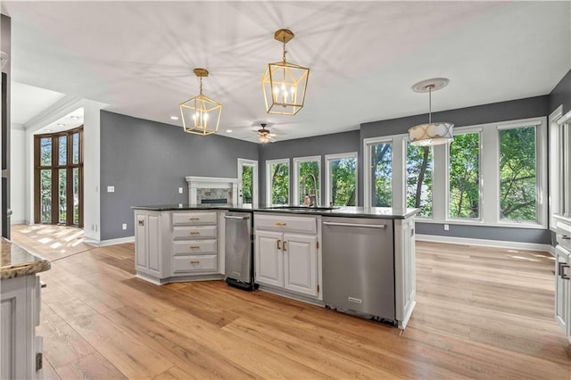 kitchen featuring light hardwood / wood-style floors, a fireplace, dishwasher, decorative light fixtures, and sink