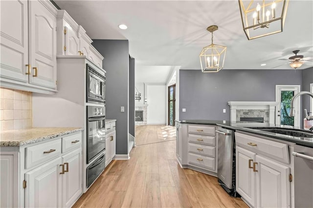 kitchen featuring white cabinets, hanging light fixtures, light hardwood / wood-style flooring, stainless steel appliances, and backsplash