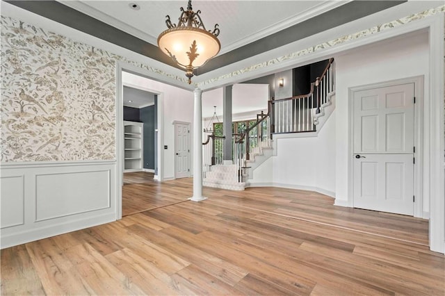 interior space featuring wood-type flooring, ornamental molding, and decorative columns