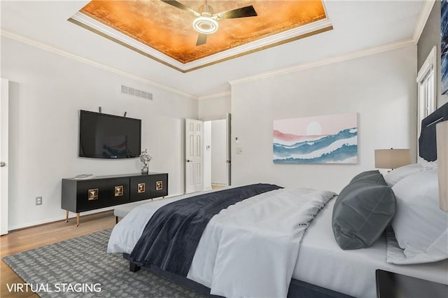 bedroom featuring ornamental molding, a tray ceiling, ceiling fan, and hardwood / wood-style floors