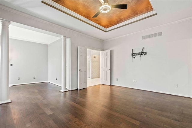 spare room featuring ceiling fan, a raised ceiling, ornamental molding, dark wood-type flooring, and decorative columns