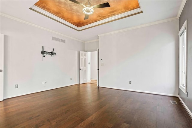 unfurnished room featuring a wealth of natural light, a raised ceiling, dark hardwood / wood-style floors, and crown molding