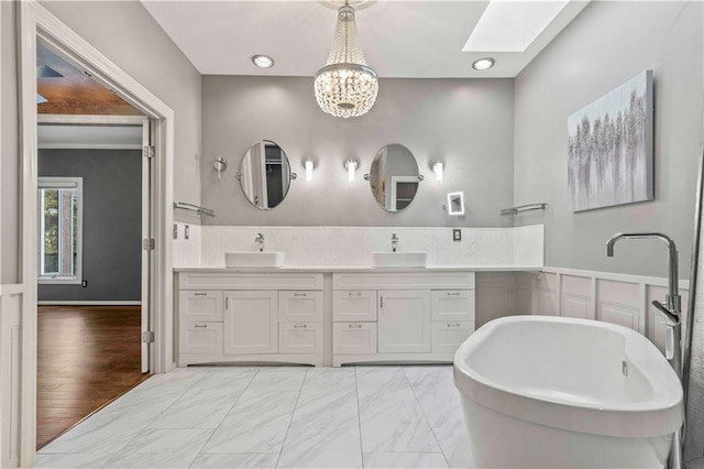 bathroom with a skylight, vanity, a washtub, wood-type flooring, and a notable chandelier