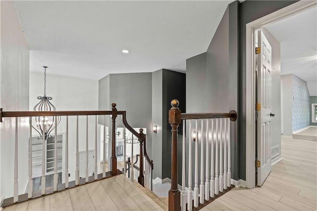 staircase featuring wood-type flooring and an inviting chandelier