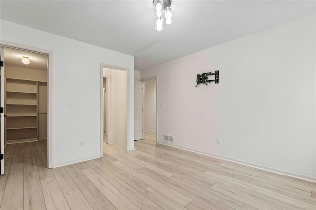 unfurnished bedroom featuring light wood-type flooring, a closet, and a walk in closet