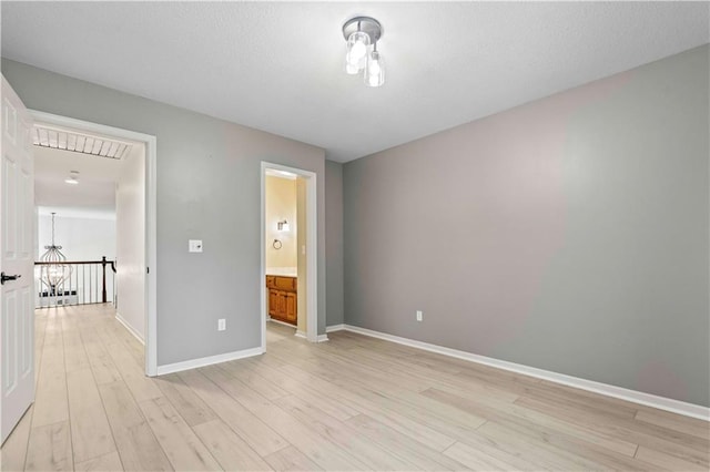 unfurnished bedroom with light hardwood / wood-style flooring and connected bathroom